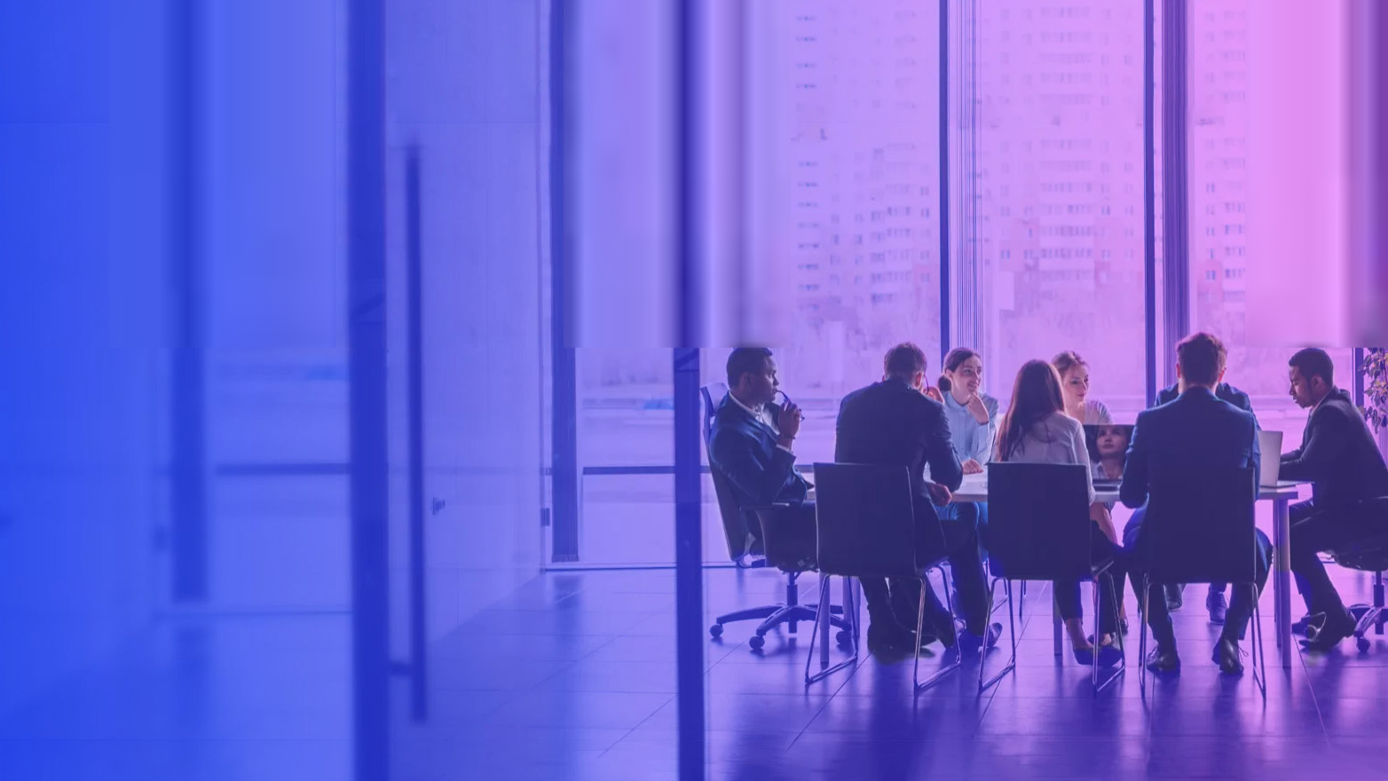 Group of male and female professionals interact around a conference table. Purple overlay over image.